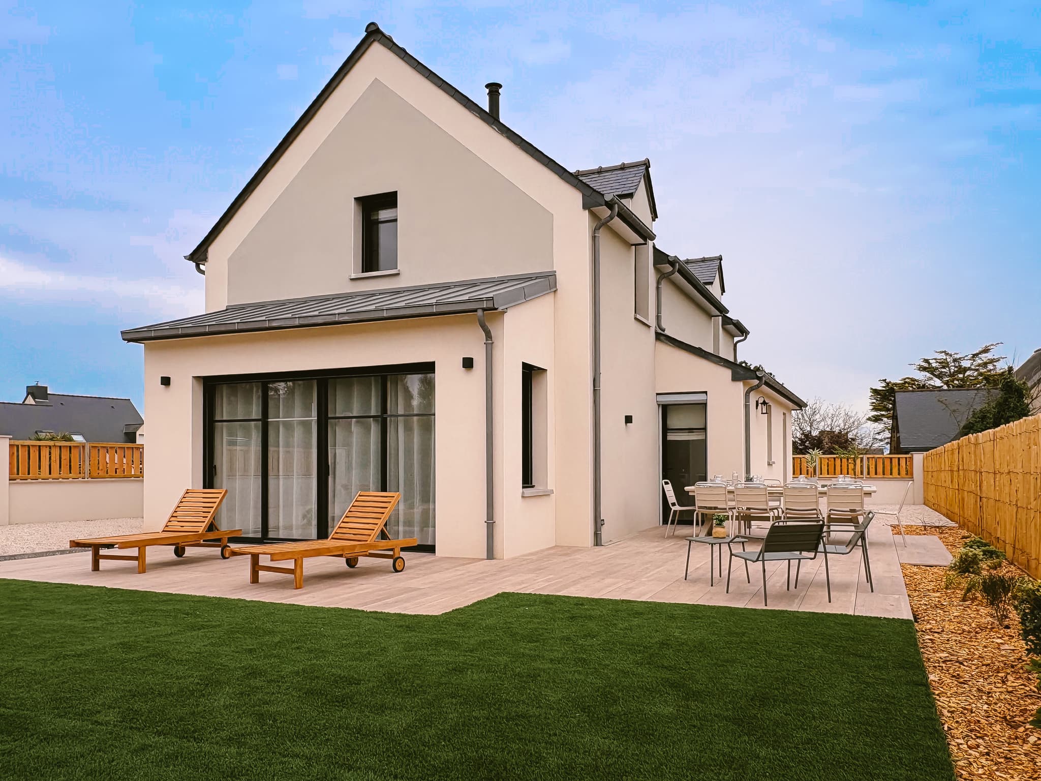 La façade de Ker Paravel et son jardin plein sud, terrasse et pergola, en fin d'après-midi.