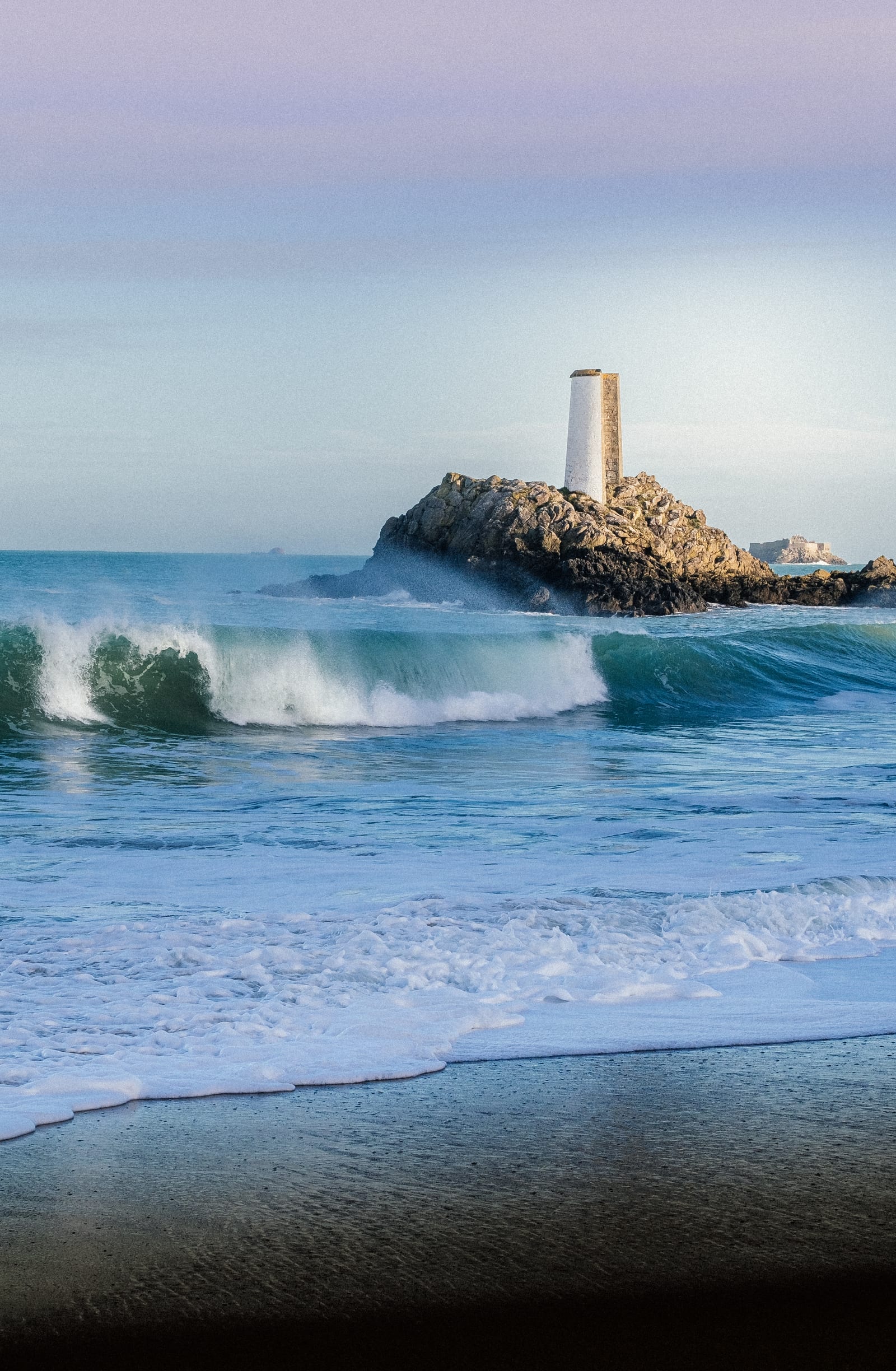 Plage de la Fourberie au crépuscule, vague et la fameuse tour blanche au loin.